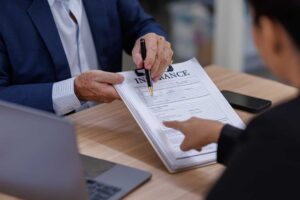 A person reviews health insurance documents and an HSA debit card at a kitchen table.