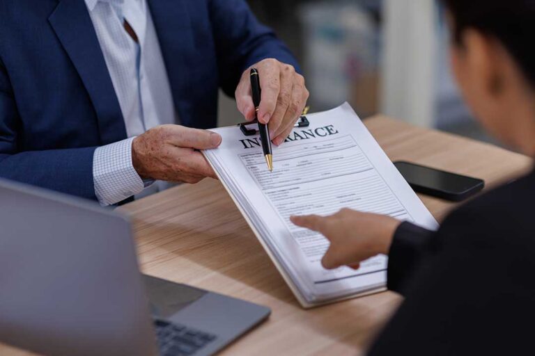 A person reviews health insurance documents and an HSA debit card at a kitchen table.