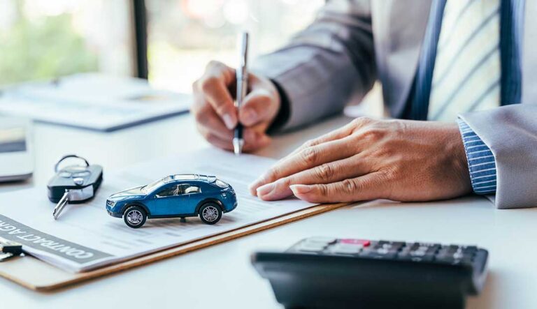 Driver reviews an auto insurance card beside a parked vehicle and vehicle registration documents.